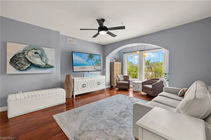 Living room with dark wood-style floors and a ceiling fan