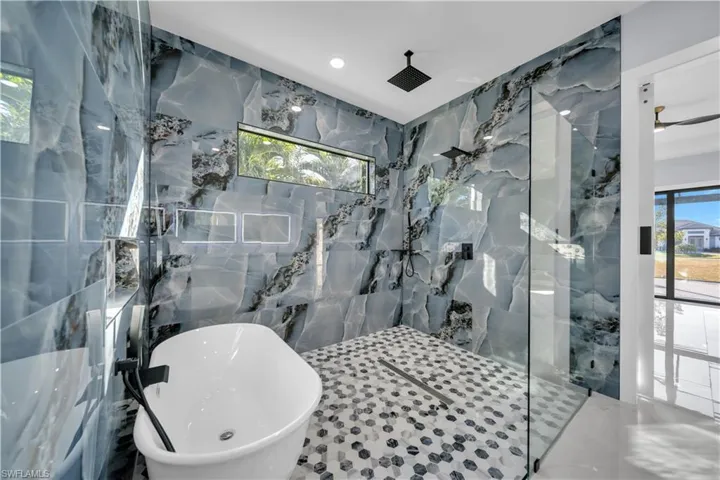 Full bath featuring tile walls, a freestanding bath, a marble finish shower, and recessed lighting