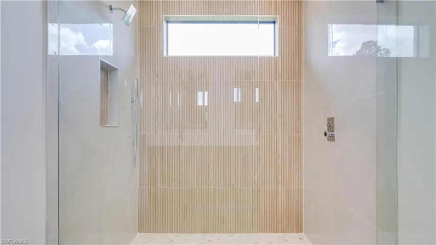 Primary walk-in shower with modern tile and multiple shower heads.