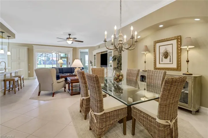 Dining area featuring light tile patterned floors, vaulted ceiling, ornamental molding, and ceiling fan