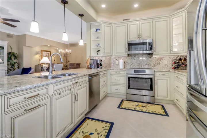 Kitchen featuring light tile patterned flooring, sink, hanging light fixtures, kitchen peninsula, and stainless steel appliances