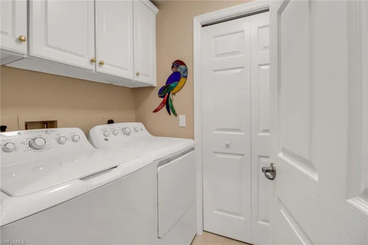 Clothes washing area featuring cabinets and washer and dryer