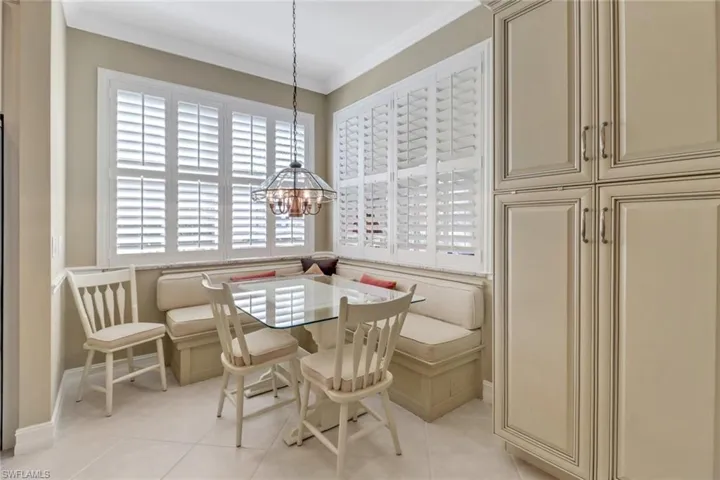 Tiled dining space featuring crown molding, an inviting chandelier, and breakfast area