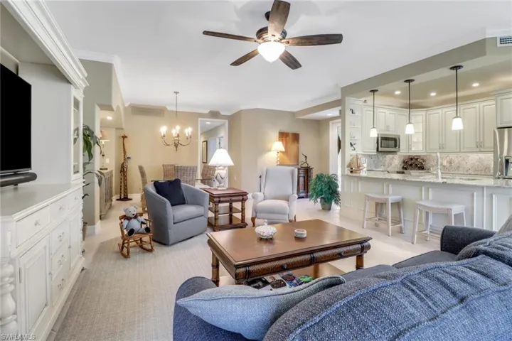 Living room with ornamental molding and ceiling fan with notable chandelier