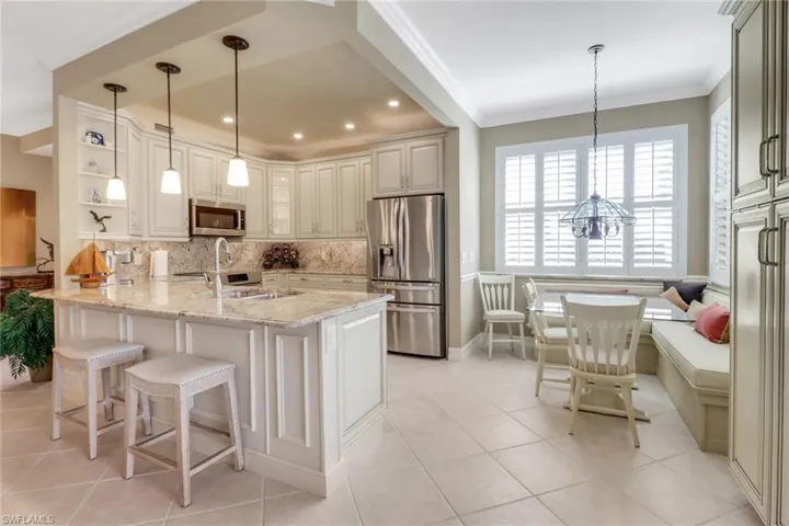 Kitchen featuring hanging light fixtures, kitchen peninsula, breakfast area, stainless steel appliances, and light stone countertops