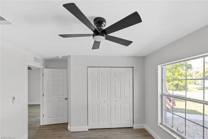 Unfurnished bedroom with a closet, wood finished floors, and a ceiling fan