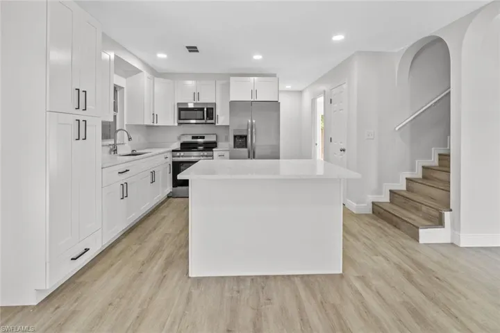 Kitchen with stainless steel appliances, white cabinetry, a center island, recessed lighting, and light wood-style floors