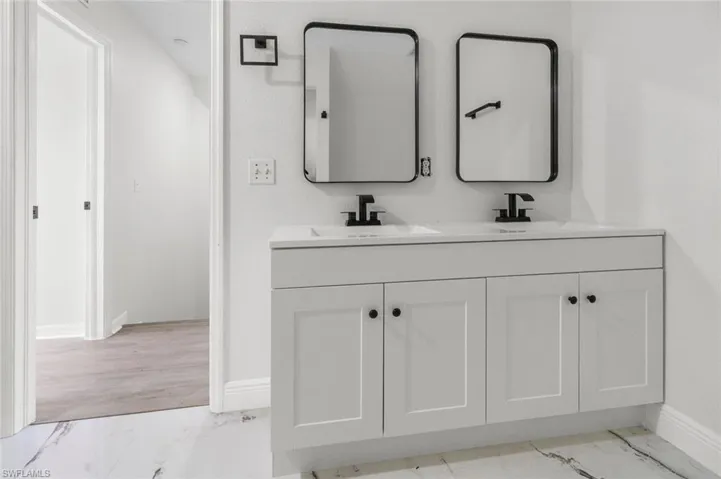Full bathroom featuring double vanity and light marble finish flooring