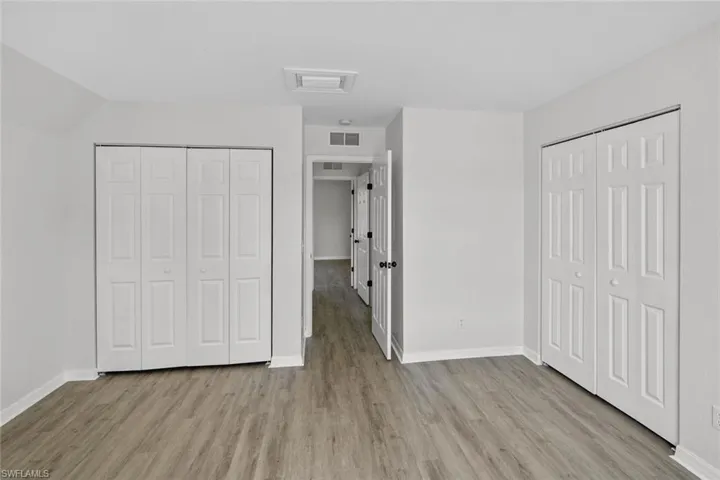 Unfurnished bedroom featuring two closets and light wood-type flooring