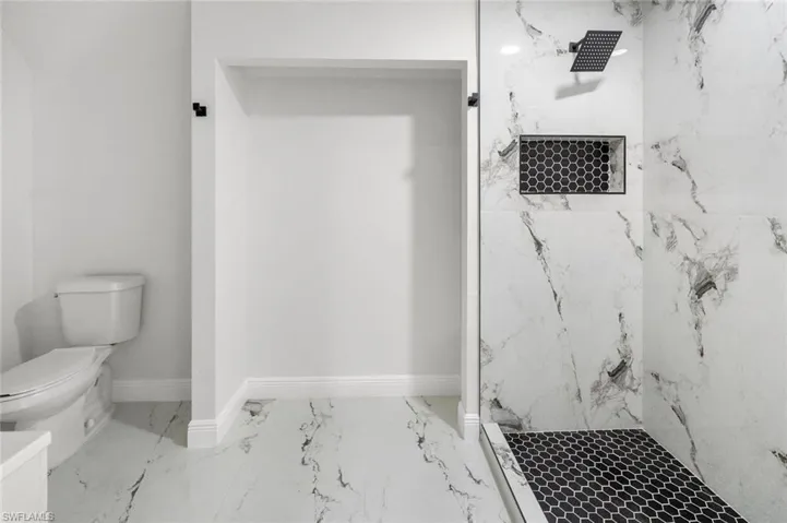Full bath with a marble finish shower and light marble finish flooring