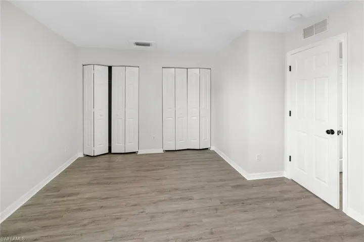 Unfurnished bedroom with two closets and wood finished floors