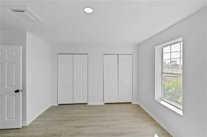 Unfurnished bedroom featuring two closets and light wood-style flooring