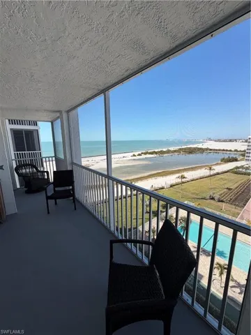 Balcony featuring view of pool and view of water and beach