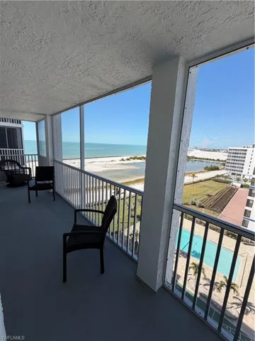 Balcony with view of water and beach and view of pool area