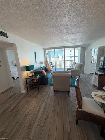Living area with a textured ceiling, wood finished floors, and a textured wall