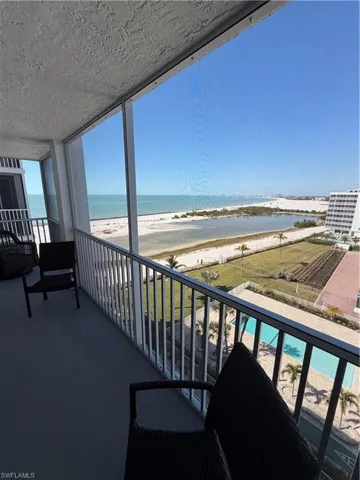 Balcony featuring a sunroom, view of water and beach, and view of pool area