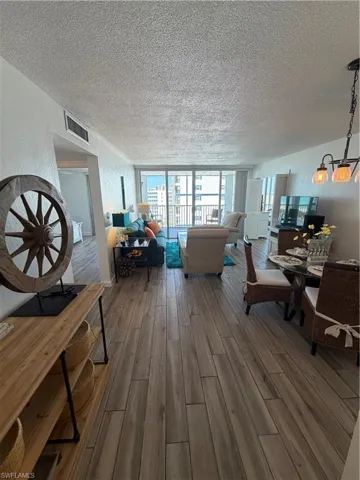 Living area featuring wood finished floors, a textured ceiling, and a textured wall