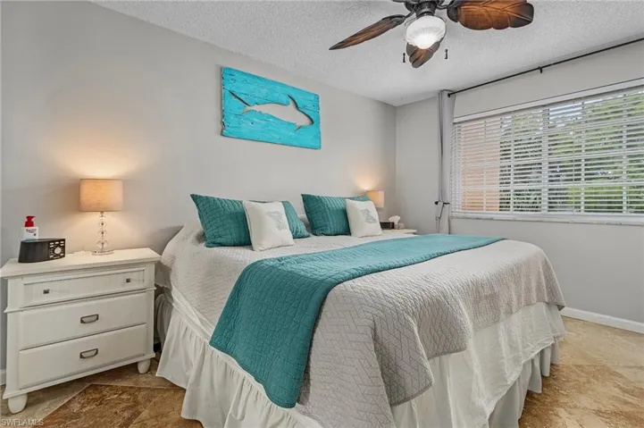 Bedroom with a textured ceiling, a ceiling fan, and stone finish flooring