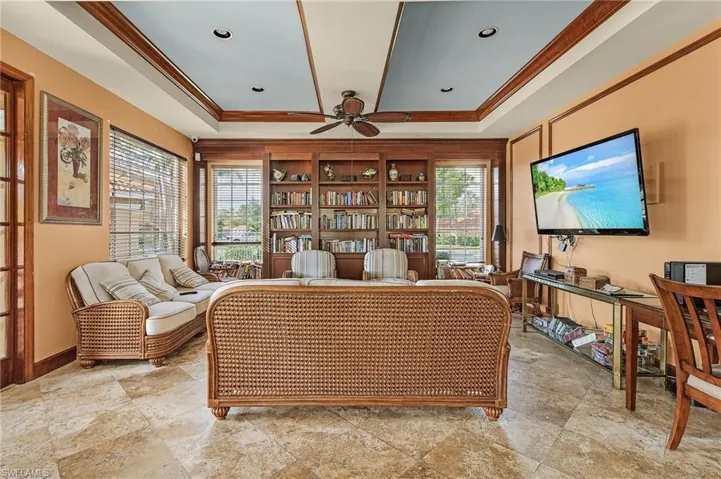 Living area with crown molding, a ceiling fan, and a tray ceiling