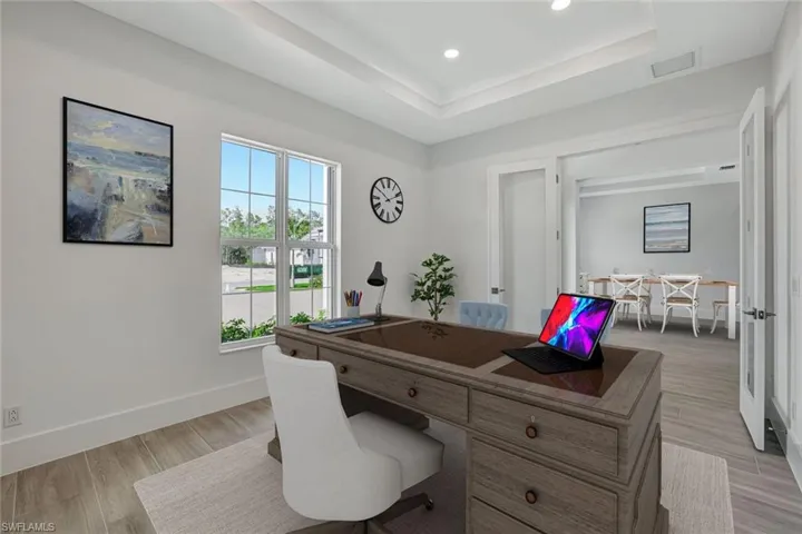 Office space featuring a tray ceiling, light wood-style floors, and recessed lighting