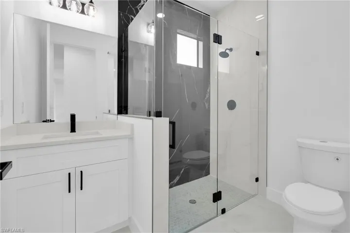 Full bath featuring a marble finish shower and vanity
