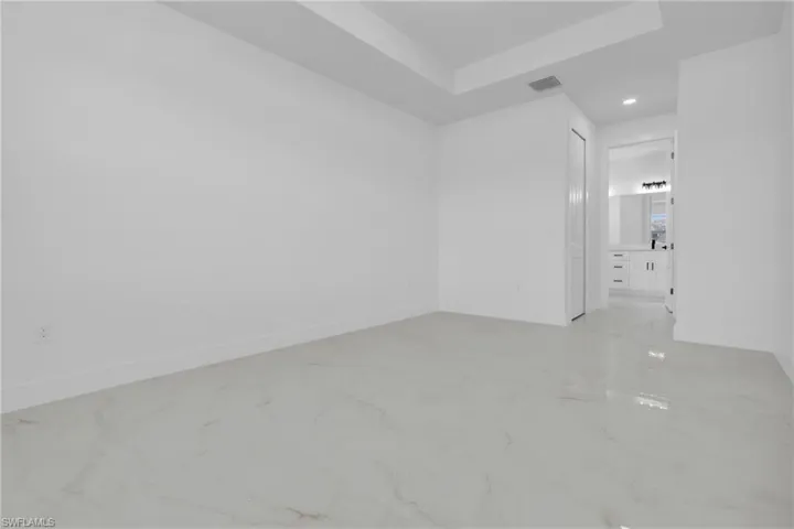 Spare room featuring recessed lighting, a raised ceiling, and light marble finish flooring