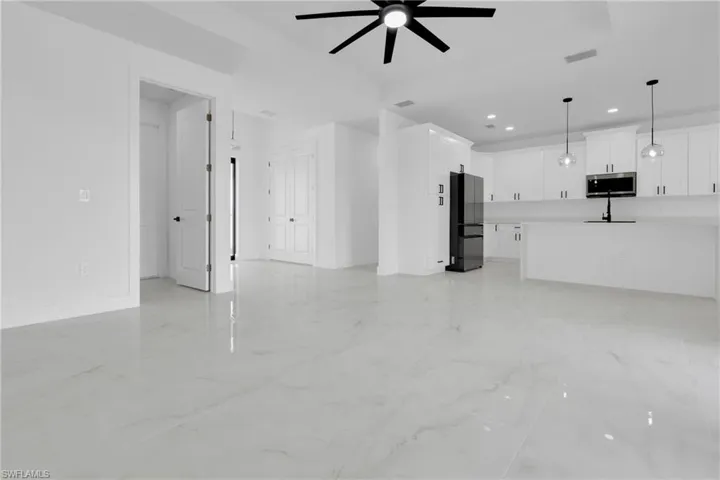 Unfurnished living room with a ceiling fan, light marble finish floors, and recessed lighting
