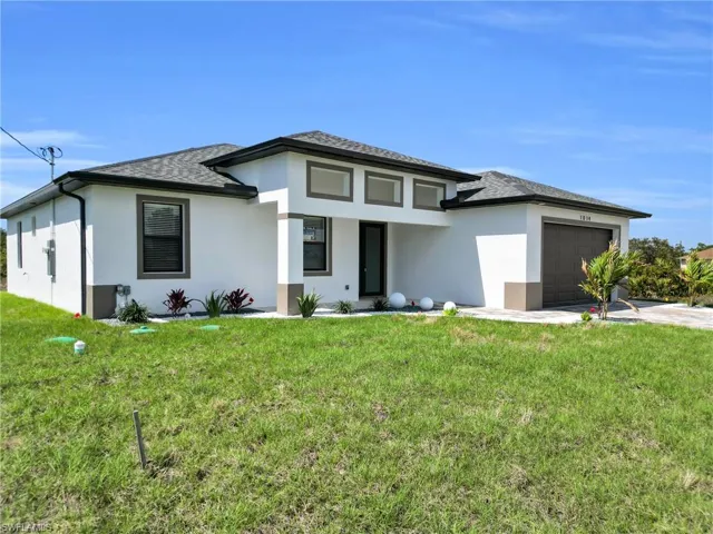 Prairie-style house with a front lawn, stucco siding, an attached garage, and concrete driveway