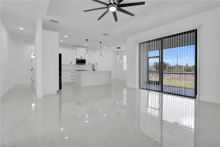 Unfurnished living room with recessed lighting, ceiling fan, and a tray ceiling