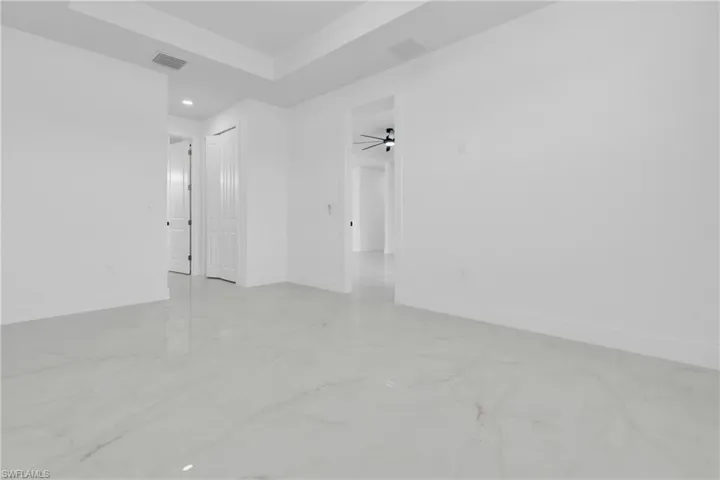Empty room featuring ceiling fan, a tray ceiling, light marble finish flooring, and recessed lighting