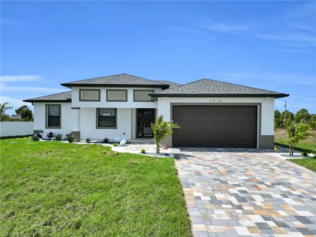Prairie-style house with a front lawn, driveway, stucco siding, and an attached garage