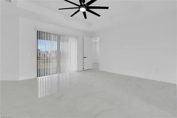 Unfurnished room with a ceiling fan, a raised ceiling, and light marble finish flooring