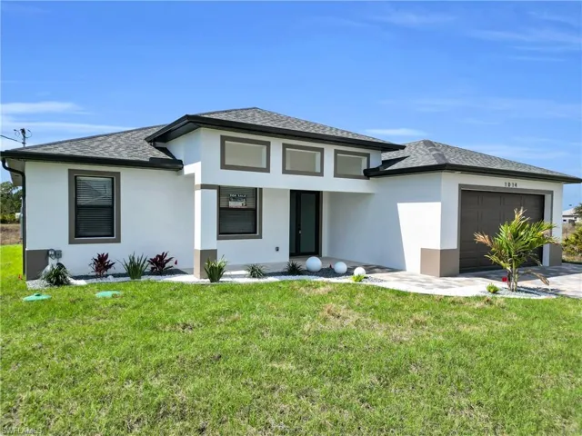 Prairie-style home with a front yard, stucco siding, and an attached garage