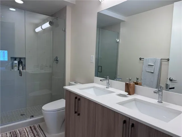 Bathroom with tile patterned flooring, an enclosed shower, vanity, and toilet