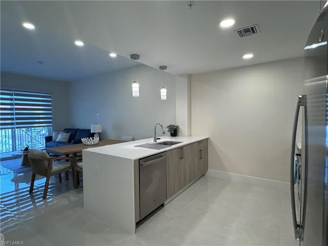 Kitchen featuring pendant lighting, kitchen peninsula, stainless steel appliances, and sink
