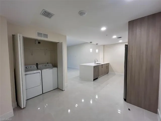 Washroom with independent washer and dryer, recessed lighting, and light tile patterned flooring