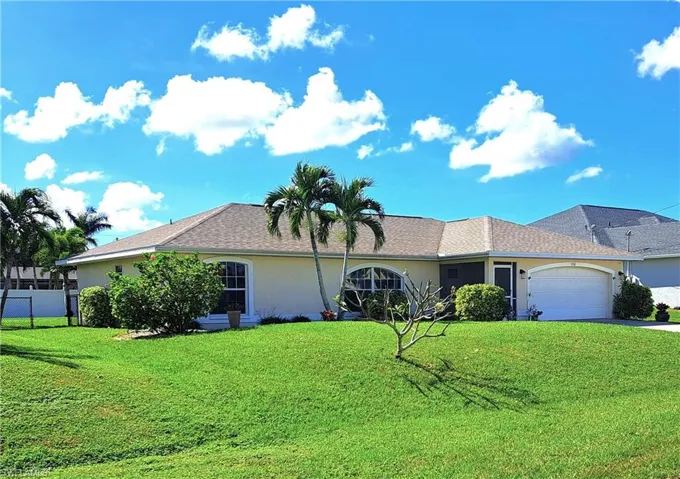 Single story home with a garage and a front lawn