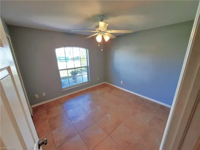 Tiled spare room featuring ceiling fan