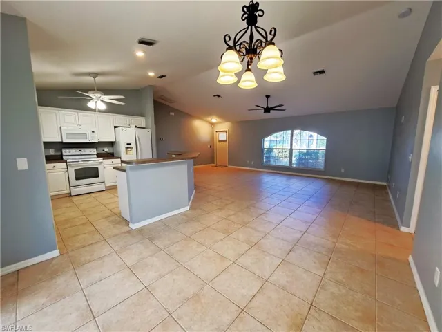 Kitchen featuring hanging light fixtures, white appliances, white cabinetry, and lofted ceiling