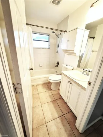 Full guest bathroom featuring tile patterned flooring, vanity, toilet, and shower / bathtub combination with curtain
