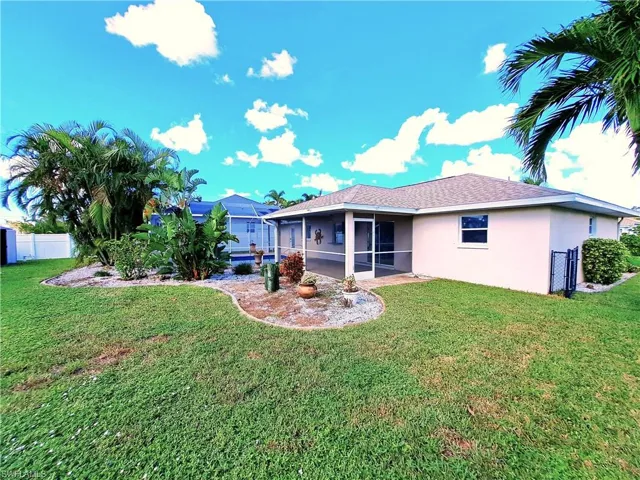 Rear view of house with a lanai and a yard