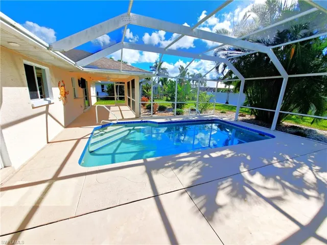 View of pool featuring ceiling fan, glass enclosure, and a patio area