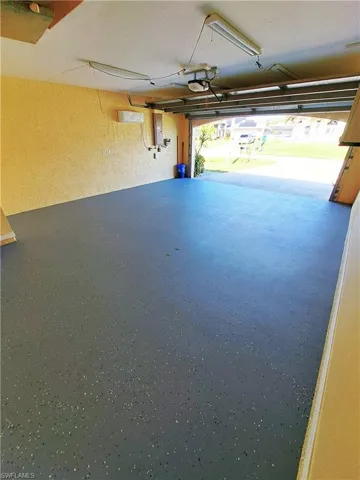 Refinished garage with electric water heater, electric panel, and a wall mounted air conditioner
