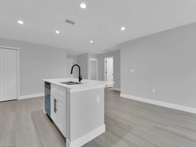 Kitchen with sink, white cabinets, a kitchen island with sink, stainless steel dishwasher, and light hardwood / wood-style floors