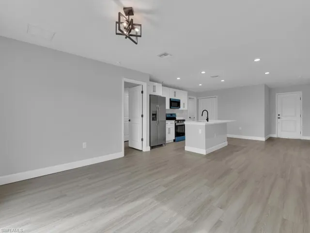 Unfurnished living room featuring sink and light hardwood / wood-style floors