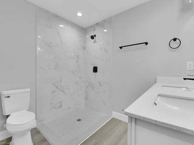 Bathroom featuring vanity, hardwood / wood-style floors, toilet, and tiled shower