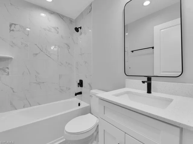 Full bathroom featuring tiled shower / bath combo, vanity, and toilet