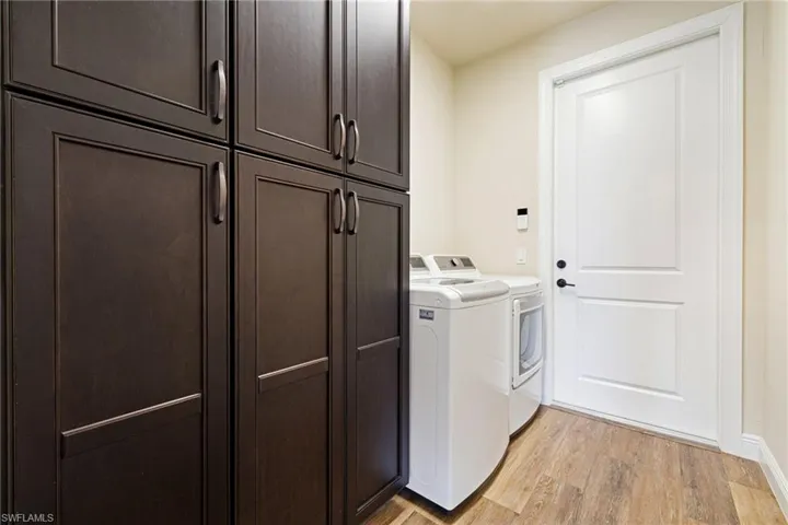 Laundry area featuring cabinet space, washer and clothes dryer, light wood-style floors, and baseboards