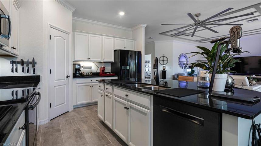 Stunning kitchen area with black granite and black stainless steel appliances.  Note the 8 foot ceiling fan.