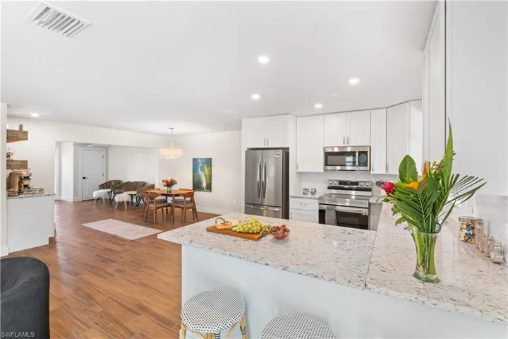 Kitchen featuring stainless steel appliances, white cabinetry, light stone countertops, and kitchen peninsula